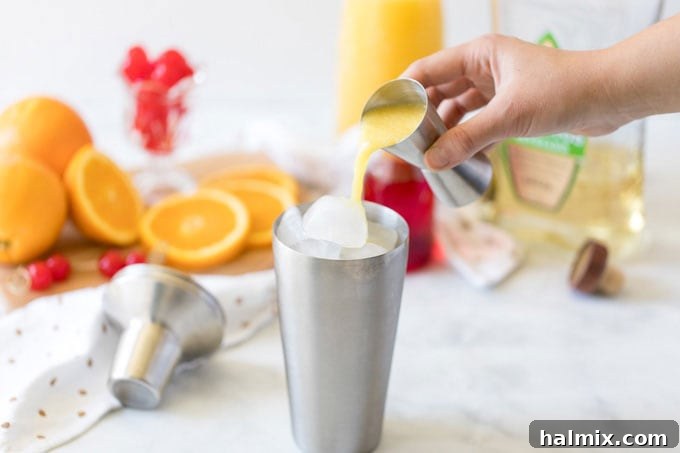 Pouring orange juice into a cocktail shaker filled with ice.