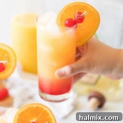 Hand holding a tequila sunrise cocktail.