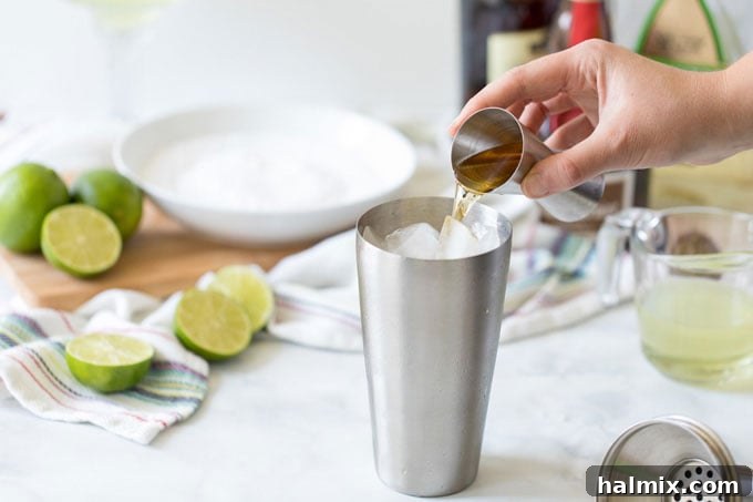 Margarita Magic 5 Adding orange liqueur to a cocktail shaker filled with ice, a key step in making a Margarita
