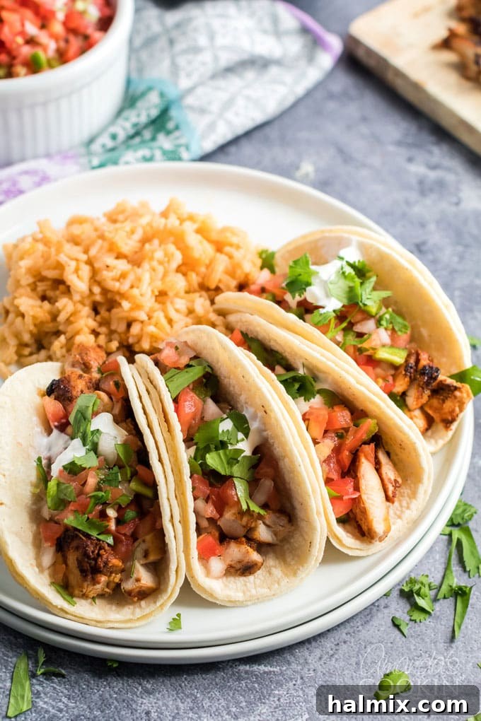 A vibrant plate of homemade chicken tacos, garnished with fresh cilantro, pico de gallo, and cotija cheese.