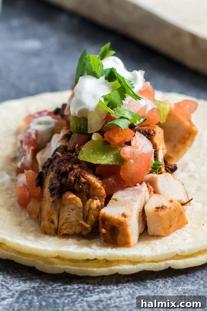 Close-up shot of seasoned chicken and fresh toppings ready for assembly on corn tortillas.