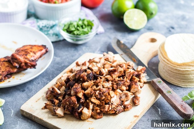 Perfectly chopped grilled chicken resting on a wooden cutting board, ready for taco assembly.