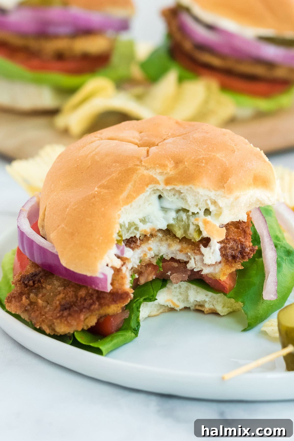 A perfectly cooked Iowa pork tenderloin sandwich with a bite taken out, showcasing the crispy breading and juicy pork.