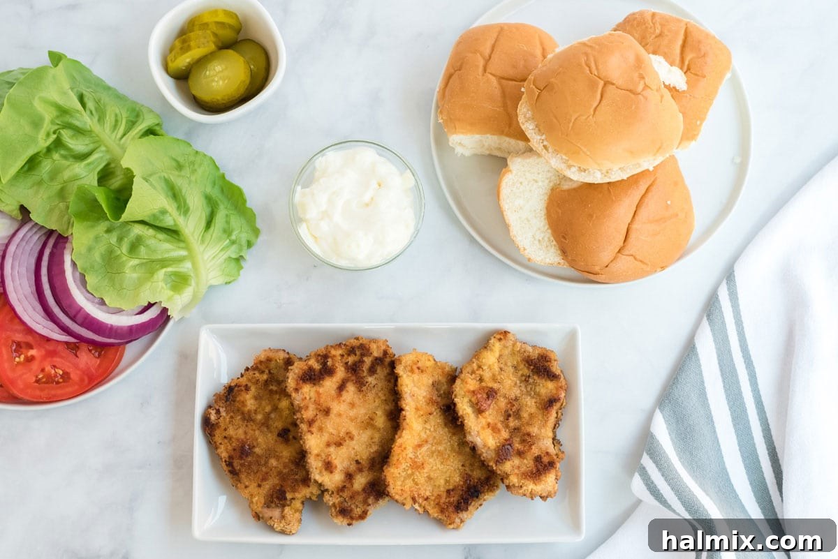 Four golden-brown, cooked breaded pork chops resting on a plate lined with paper towels to absorb excess oil.