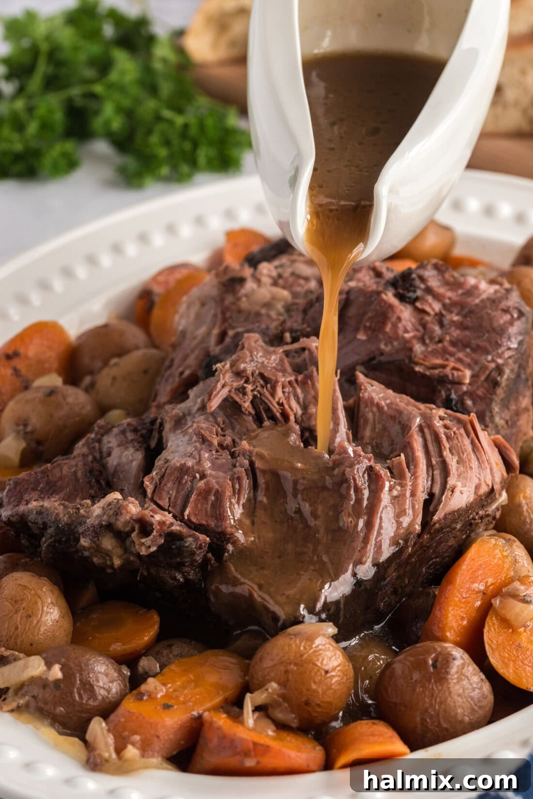 Perfect Slow Cooker Pot Roast 3 Gravy being poured over Crockpot Roast Beef on a platter