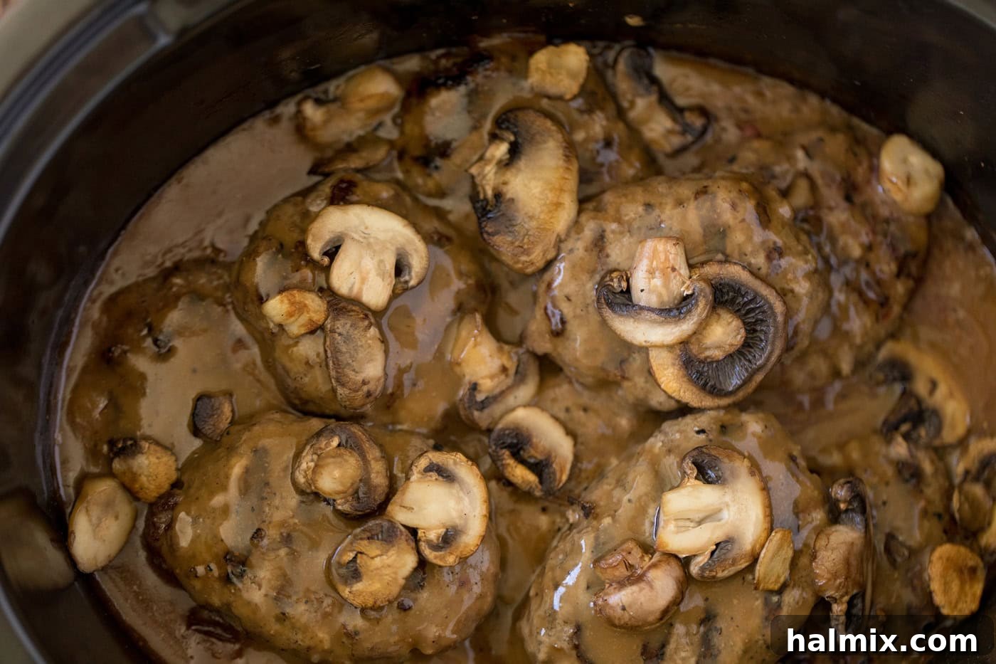 Hearty Salisbury Steaks 11 Mushrooms, rich gravy, and tender Salisbury steak patties simmering in a slow cooker, showcasing the slow-cooked perfection.