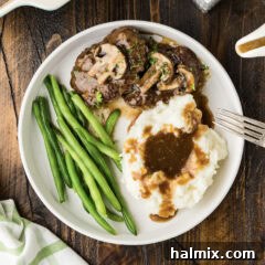 Hearty Salisbury Steaks 13 A dinner plate featuring two Salisbury steaks covered in savory gravy, accompanied by side dishes.
