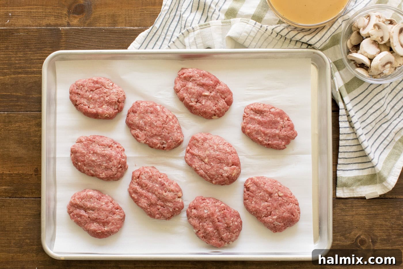 Hearty Salisbury Steaks 6 Oval-shaped Salisbury steak patties neatly arranged on a parchment-lined baking sheet, ready for browning.