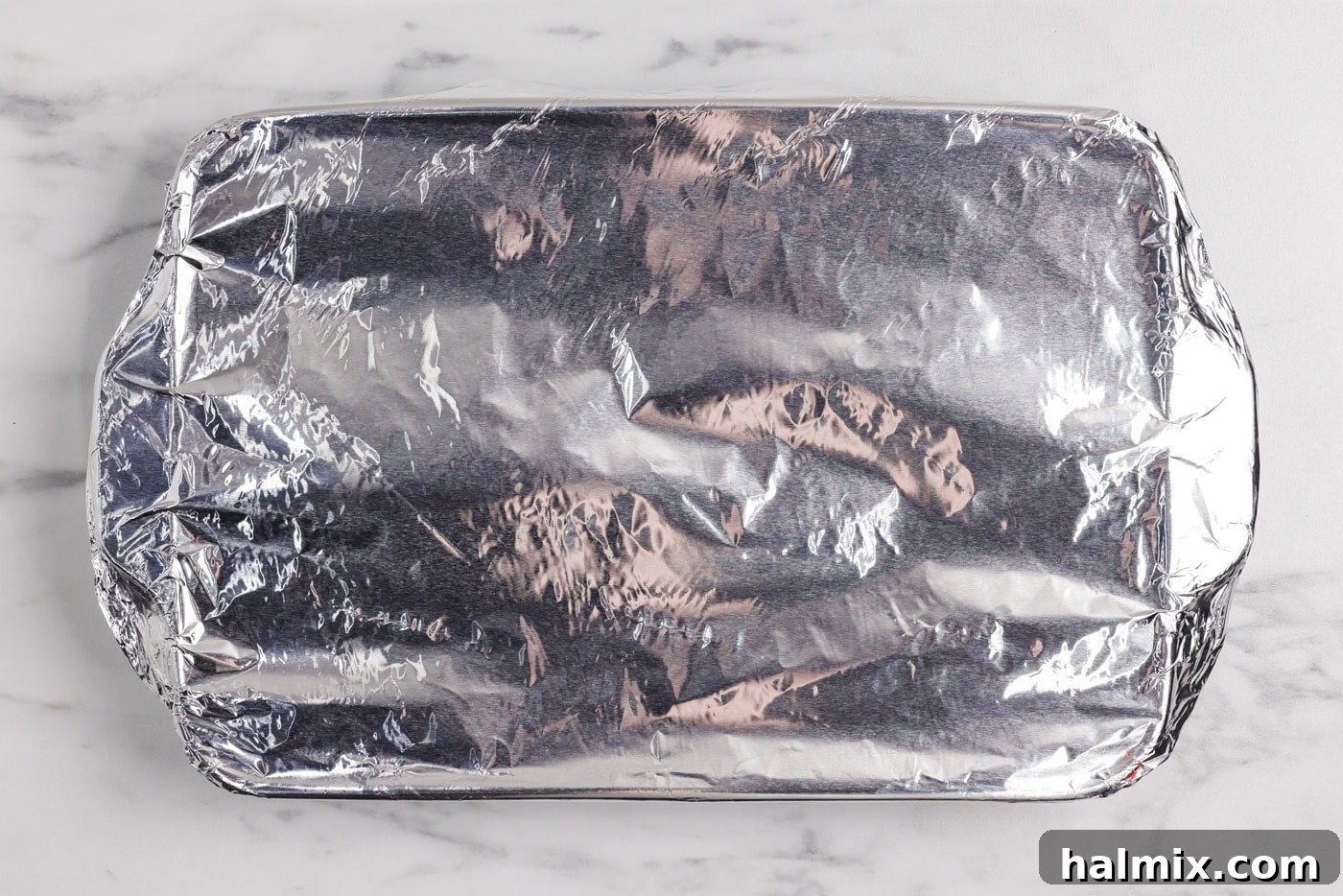 Hearty Salisbury Steaks 9 An overhead view of a baking dish securely covered with aluminum foil, indicating it's ready for baking.