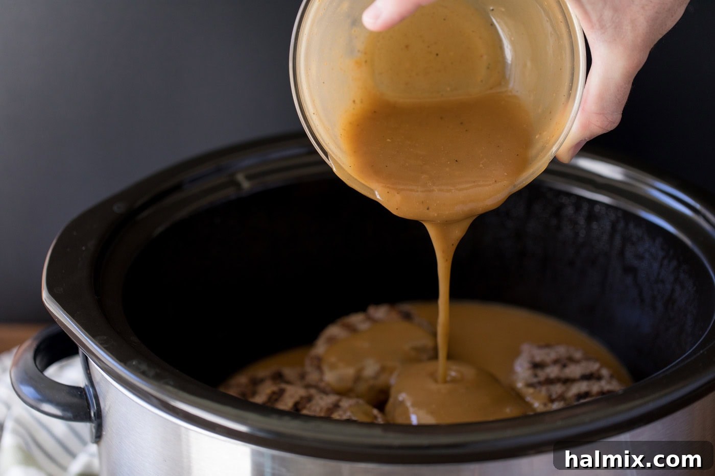 Hearty Salisbury Steaks 10 Thick brown gravy poured over seared Salisbury steak patties in a slow cooker, ready for slow cooking.