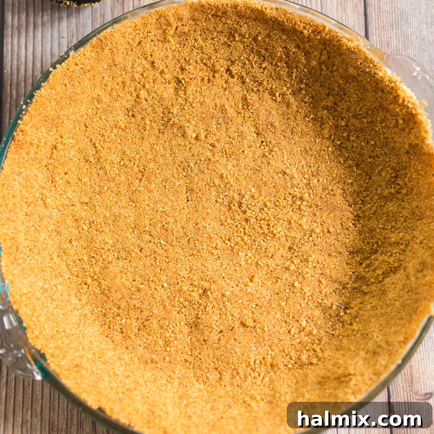 The graham cracker crust meticulously pressed into a 9-inch pie plate, forming an even layer