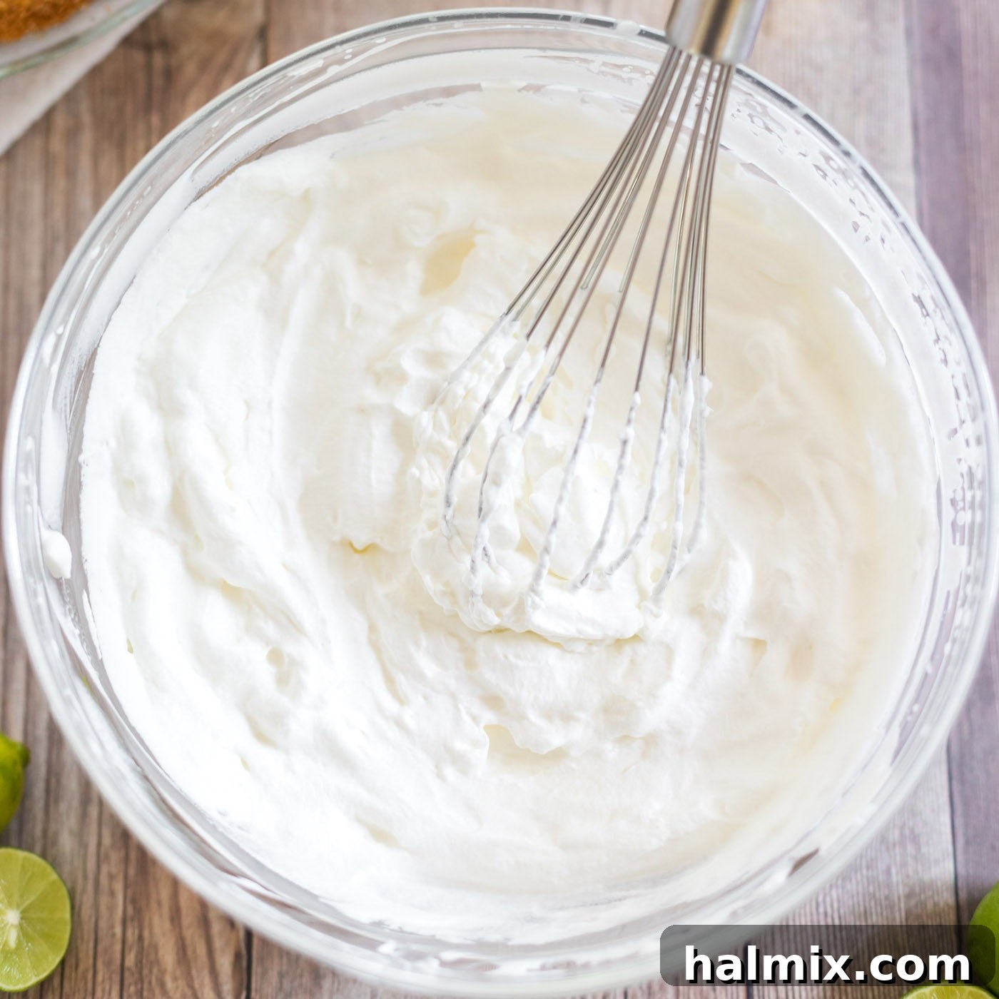 Freshly whipped cream with a whisk in a chilled bowl, showing perfect soft peaks