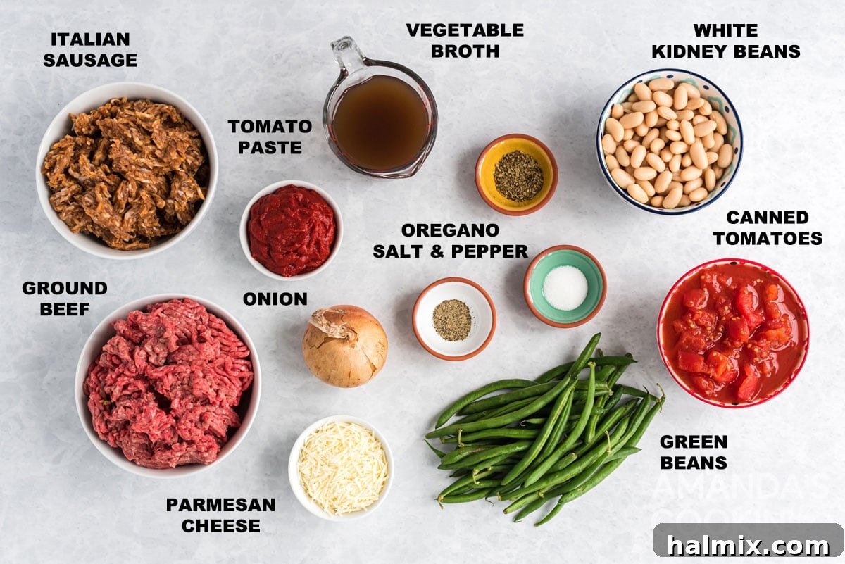 All the fresh and canned ingredients for Italian Hamburger Stew laid out and clearly labeled on a wooden surface, including ground beef, sausage, cannellini beans, green beans, stewed tomatoes, broth, tomato paste, and spices.