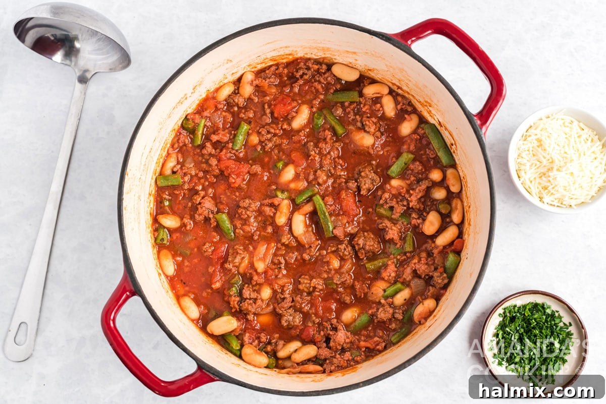 A pot of hearty Italian Hamburger Stew simmering gently on the stovetop, with steam rising, indicating it's nearly ready to serve.