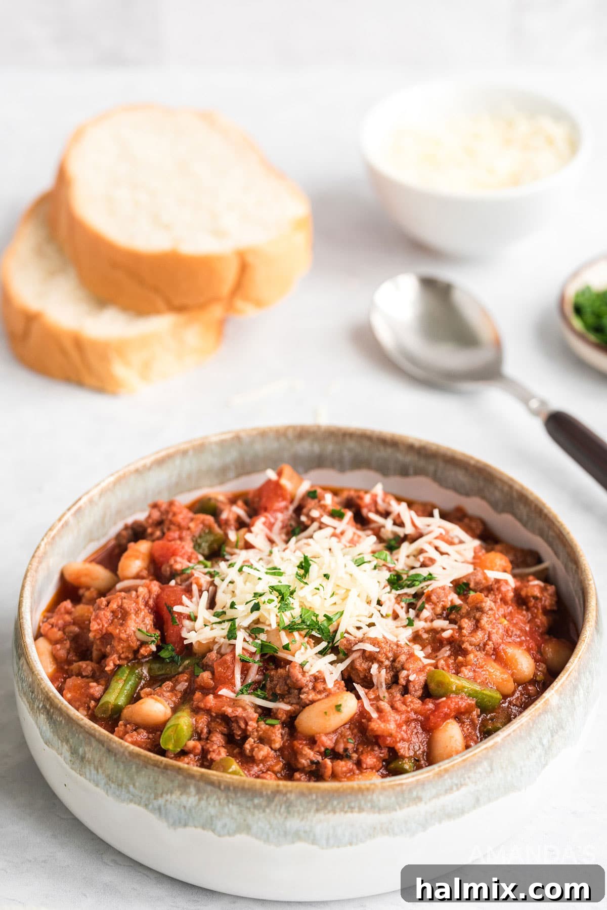 A serving of Italian Hamburger Stew in a bowl, accompanied by slices of warm, crusty bread, perfectly ready to be enjoyed as a comforting meal.