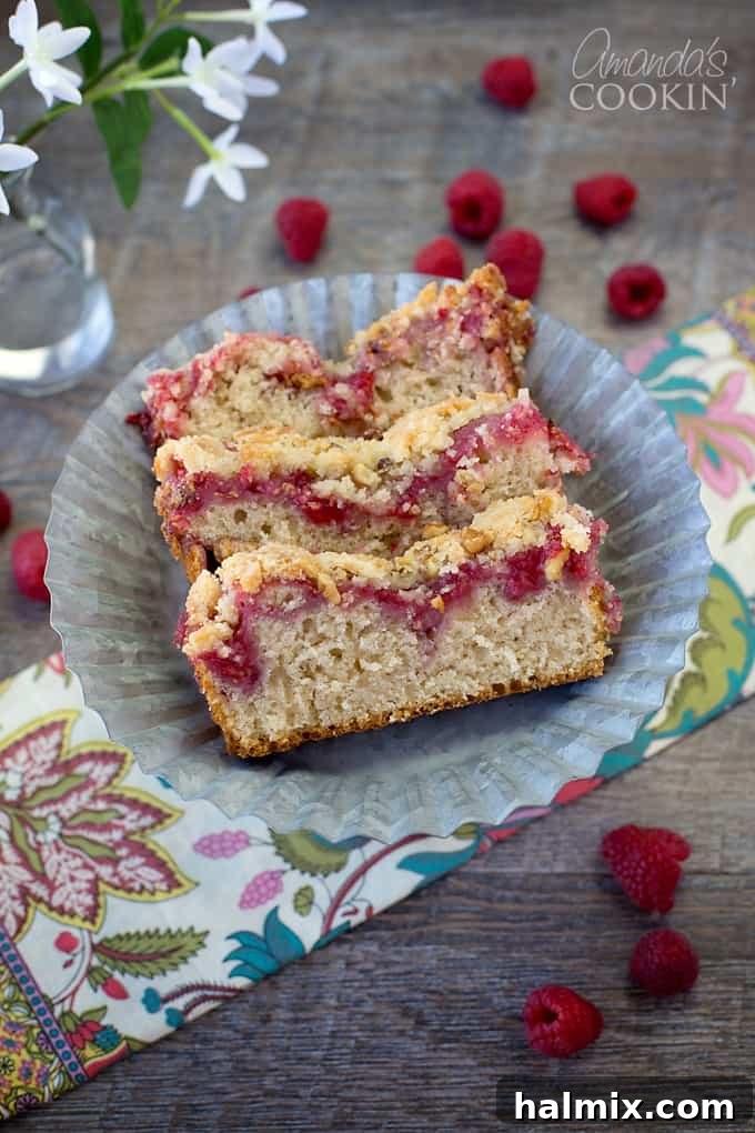 An overhead picture of three tempting raspberry coffee cake slices on a rustic wooden board, ready to be enjoyed.