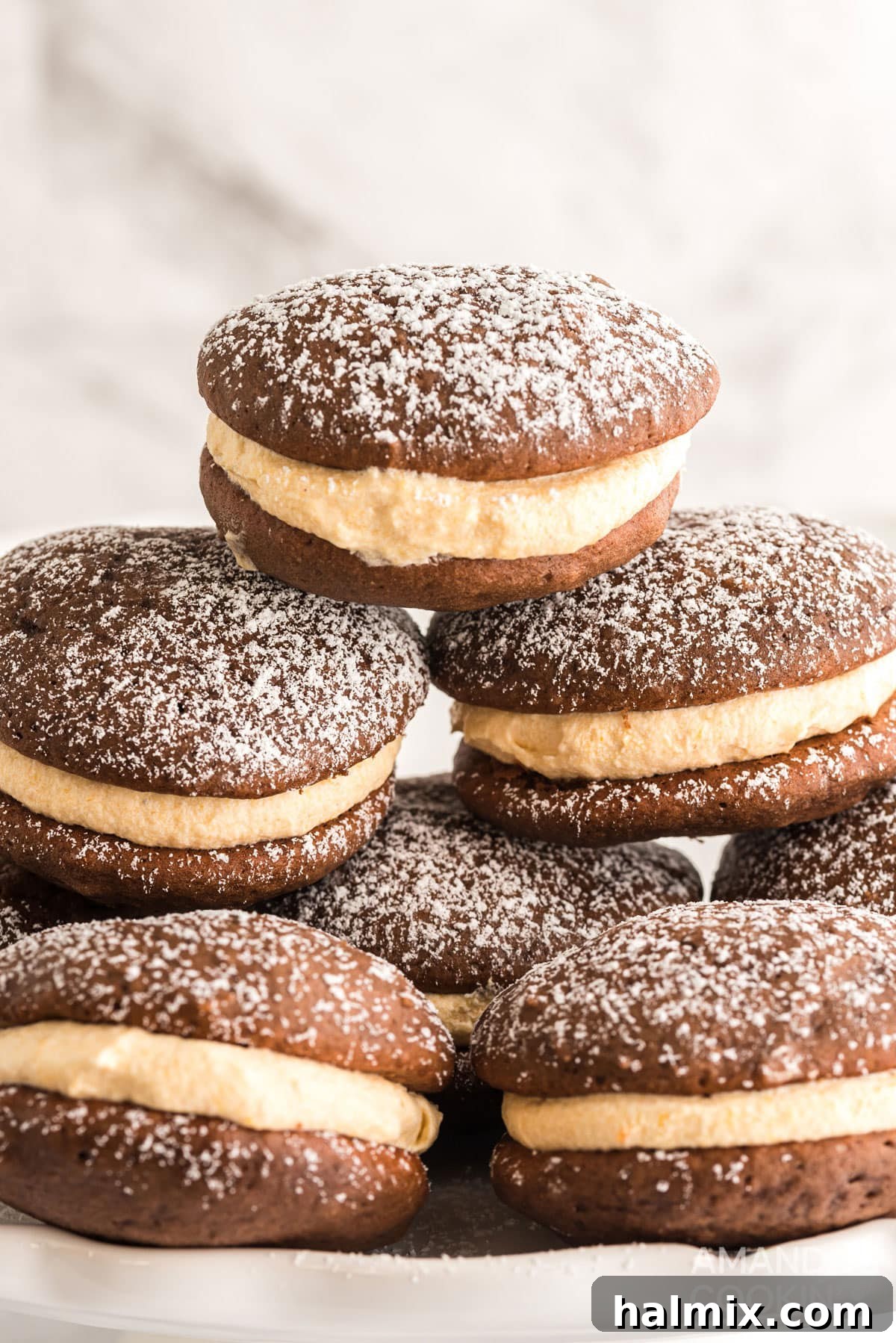 A close-up shot of a stack of mini pumpkin whoopie pies, lightly dusted with powdered sugar, showcasing their soft texture and inviting fall colors.