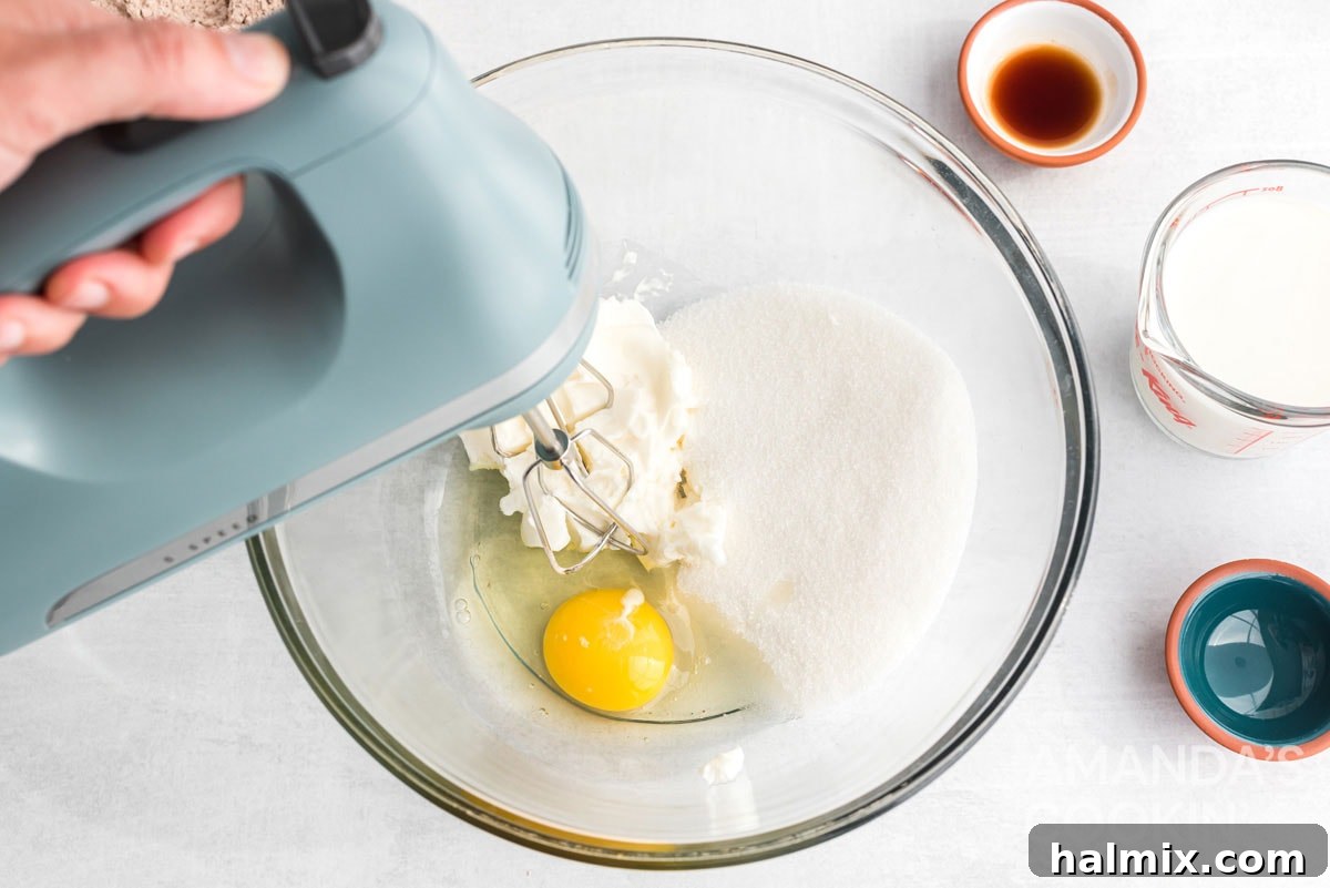 Close-up of a mixer combining egg with sugar and shortening in a large bowl, illustrating the initial creamy stage of cookie dough preparation.