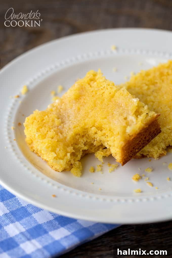 Delicious Sweet Cornbread 2 A slice of golden-brown sweet cornbread with a bite taken out, resting on a rustic wooden surface, showcasing its moist interior.