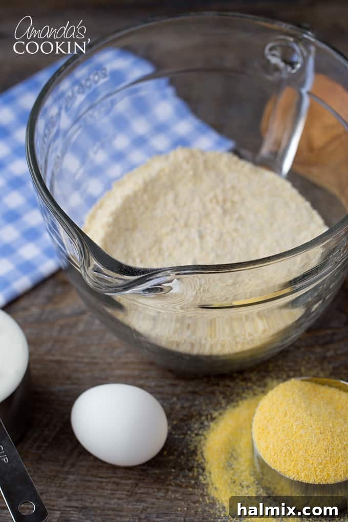 Delicious Sweet Cornbread 4 A top-down view of all the dry ingredients for sweet cornbread (flour, cornmeal, sugar, baking powder, baking soda, salt) meticulously arranged in a large mixing bowl, ready for combining.
