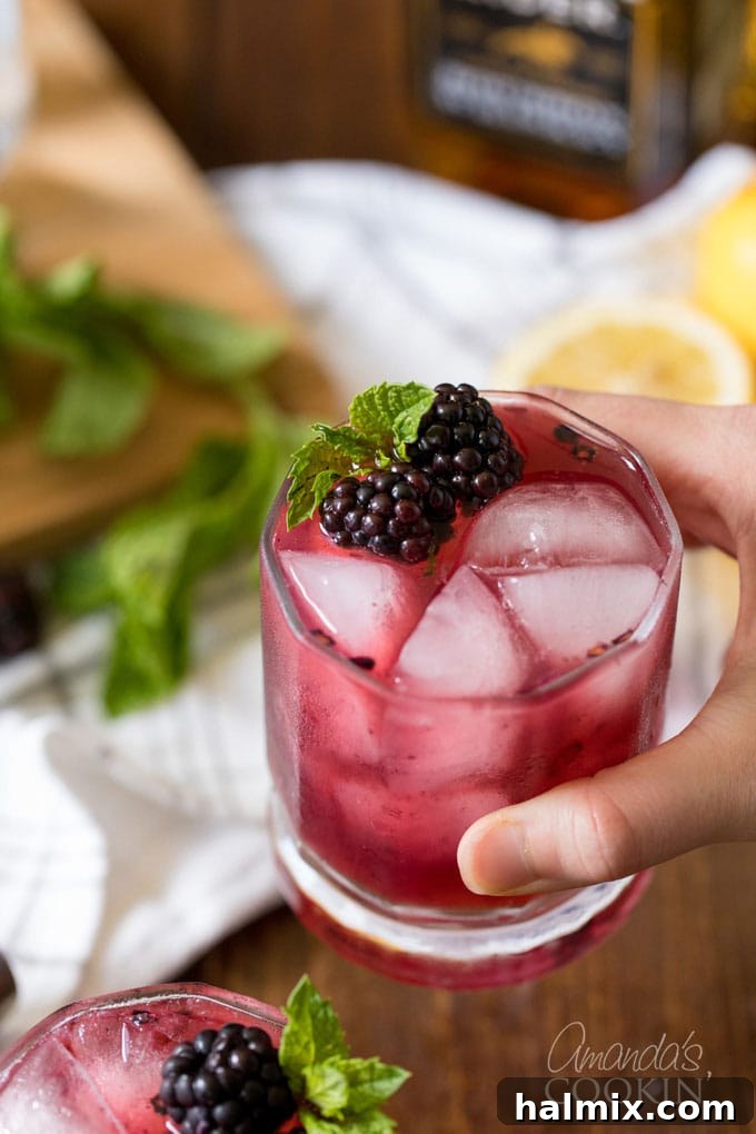 Twilight Berry Bourbonade 8 hand holding a glass of blackberry lemonade with whiskey