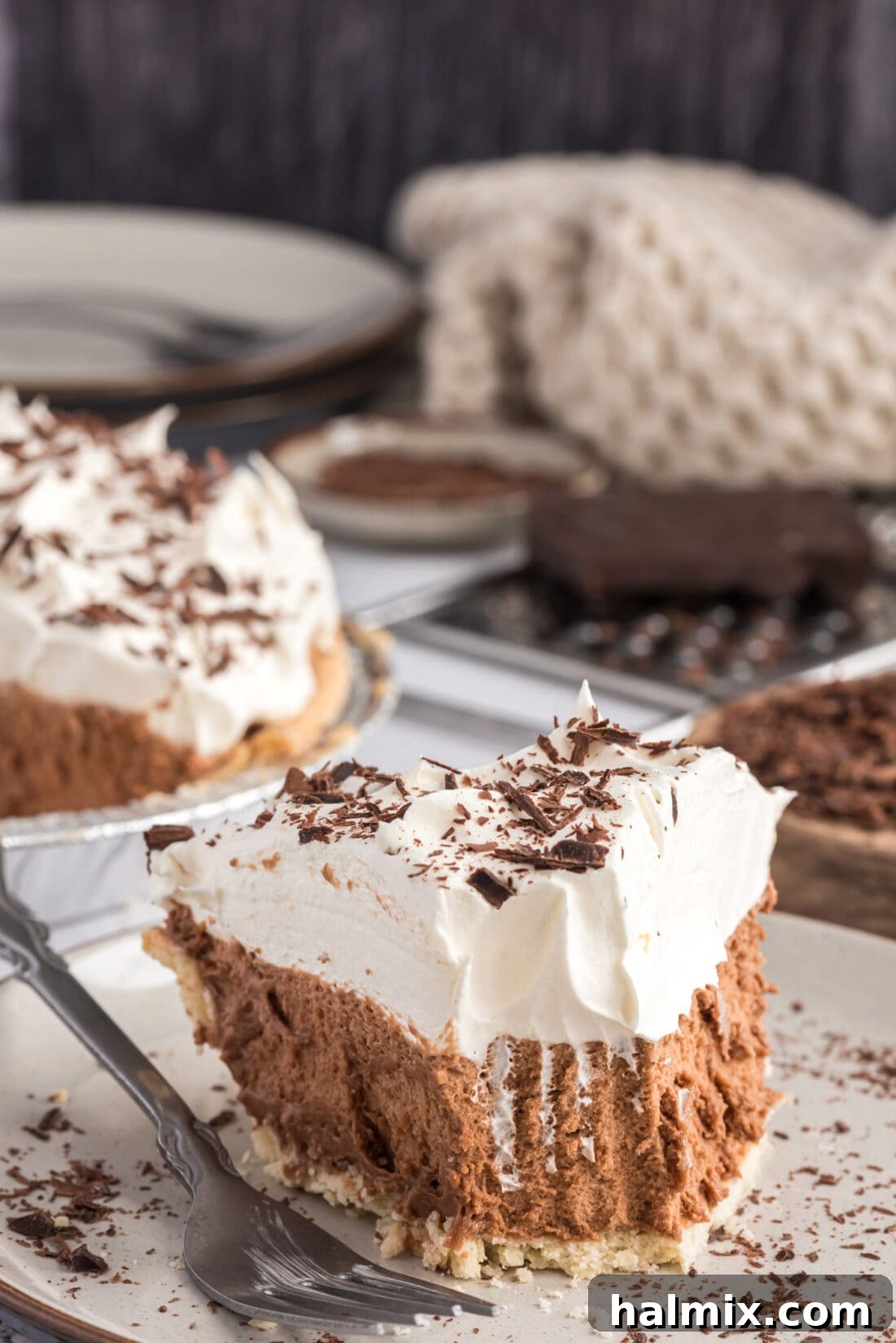 Decadent French Silk Delight 2 A delectable slice of French Silk Pie on a white plate with a bite removed, showcasing its rich chocolate filling and airy whipped cream topping.