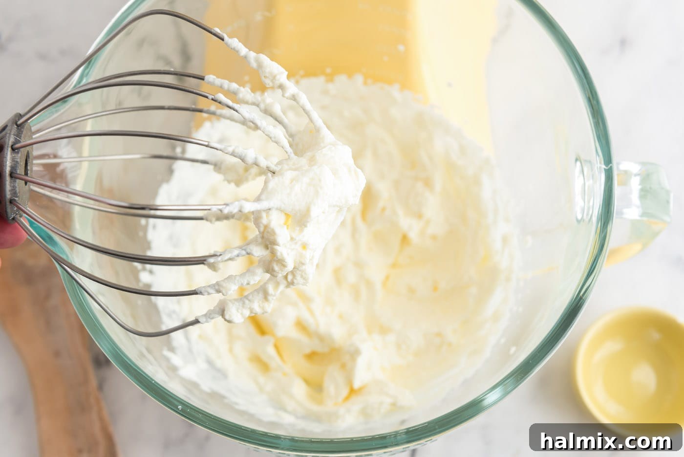 Homemade whipped cream on a whisk attachment, showing perfect stiff peaks.