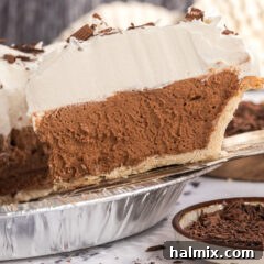 Close up photo of a slice of French Silk pie being lifted out of the pie dish, showcasing its creamy texture.