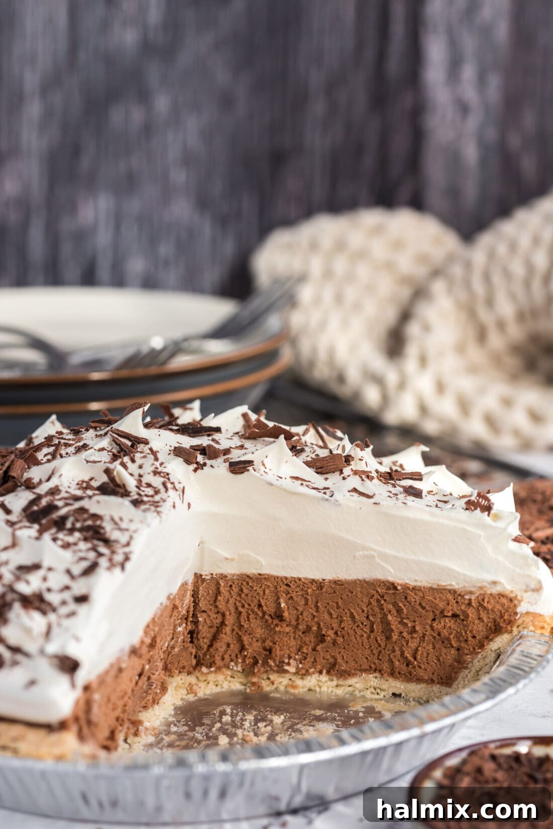 Decadent French Silk Delight 3 A full French Silk Pie with several slices already removed, showcasing its pristine whipped cream topping and the smooth, dark chocolate filling.