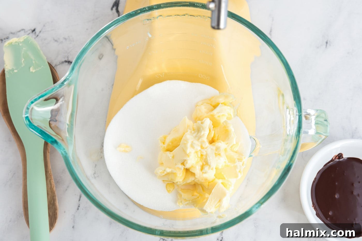 Softened butter and granulated sugar inside a stand mixer bowl before mixing.