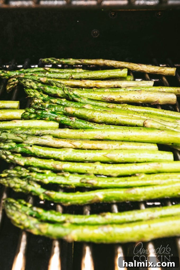 fresh asparagus spears being placed directly onto hot grill grates, showing a slight char