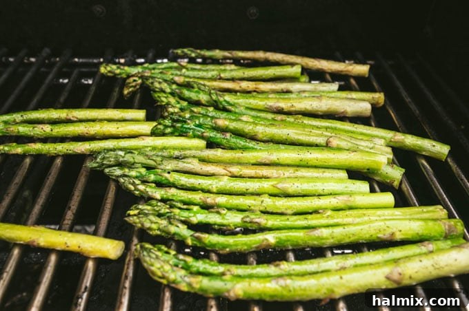 close-up of asparagus spears with visible grill marks cooking on the hot grill grates