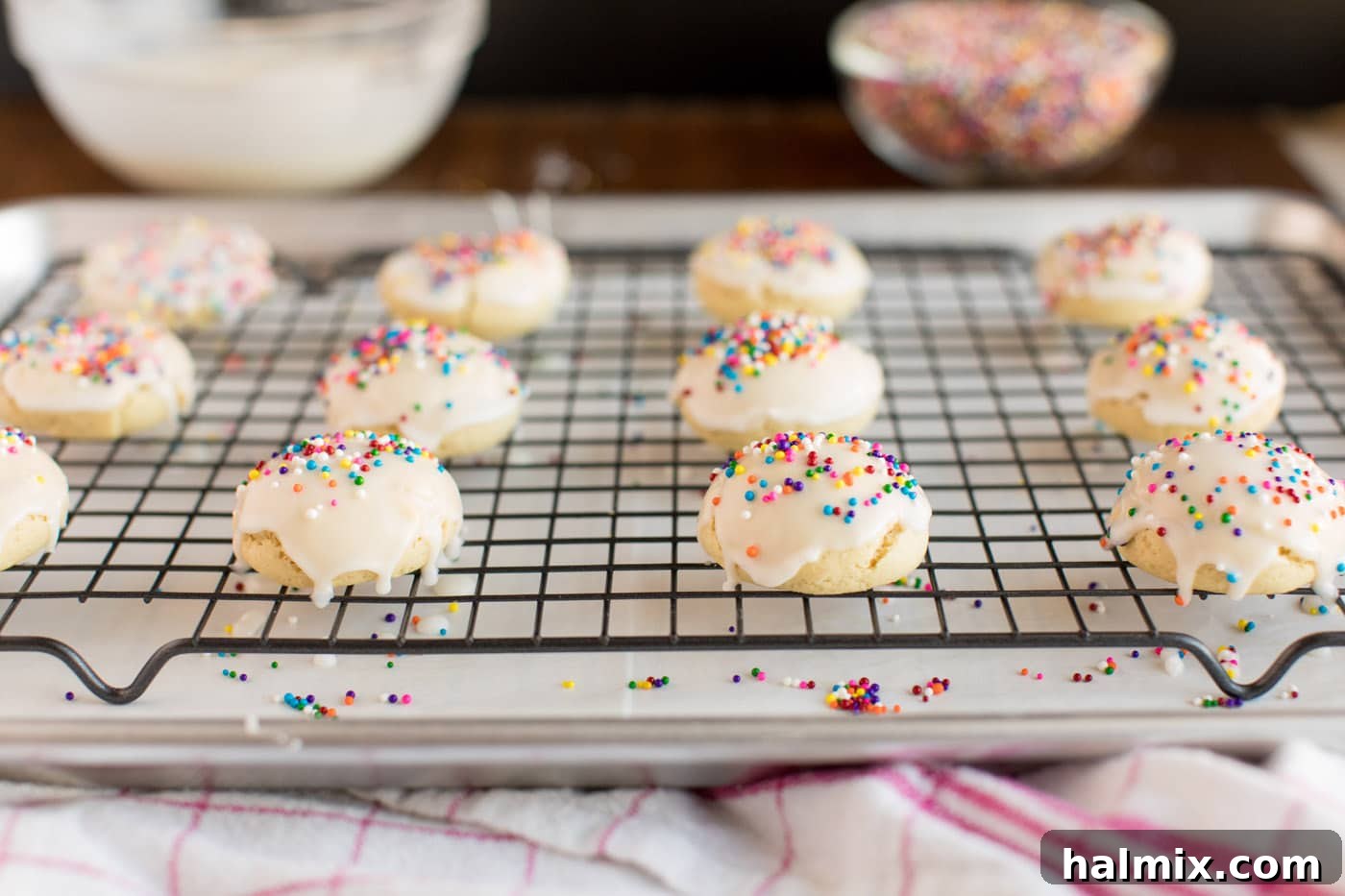 Glazed cookies adorned with colorful sprinkles, arranged on a wire rack.