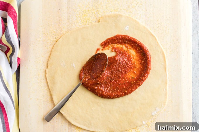 Perfect Homemade Pizza Crust 12 adding sauce to pizza dough on a pizza peel