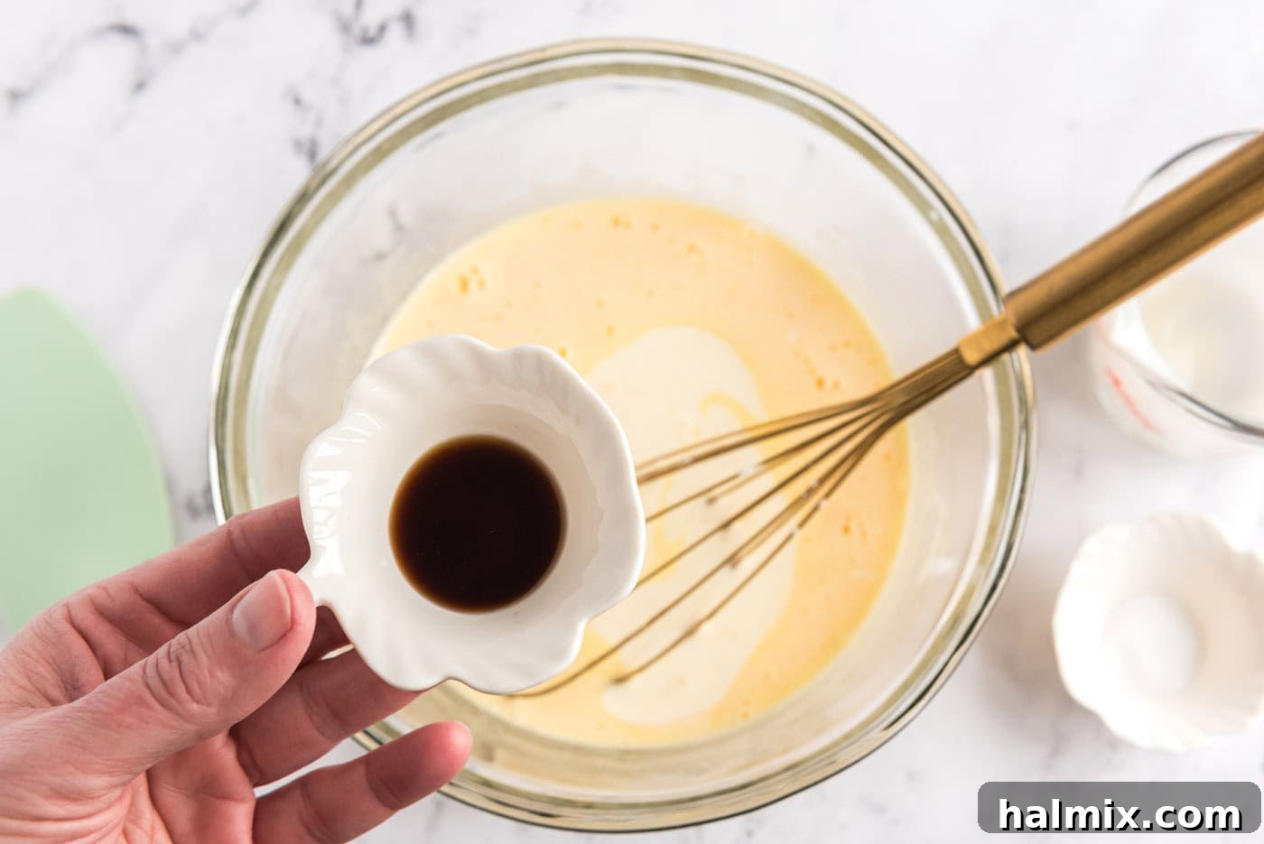 adding vanilla to whisked eggs, sugar, and heavy cream mixture