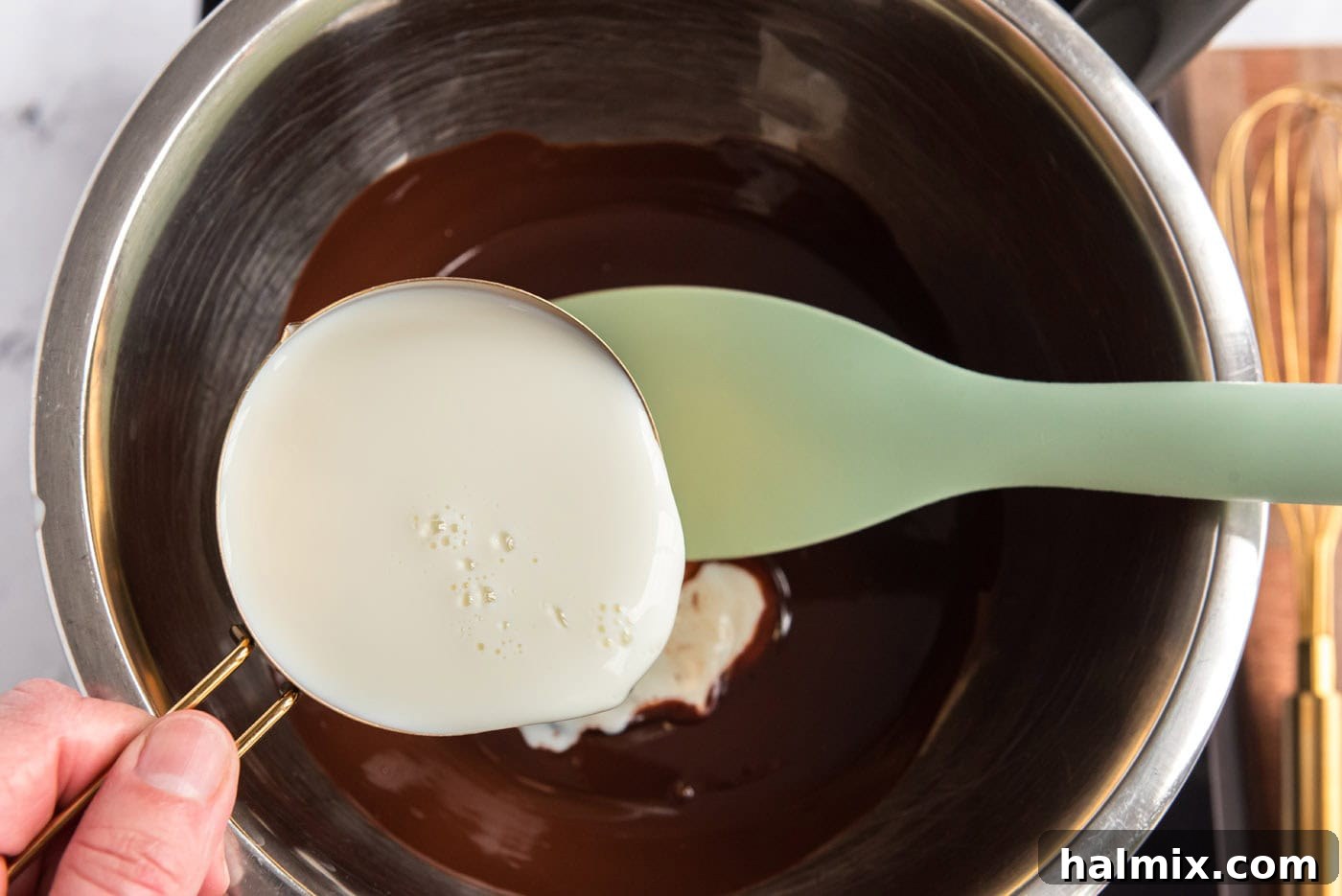whisking milk into melted chocolate in a large bowl