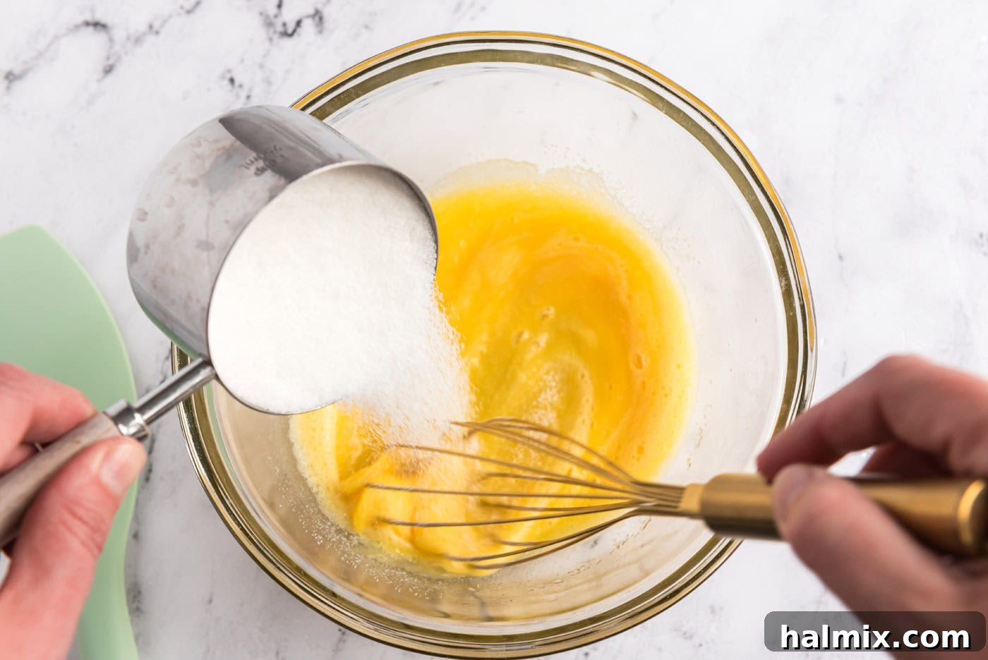 whisking sugar into eggs in a bowl