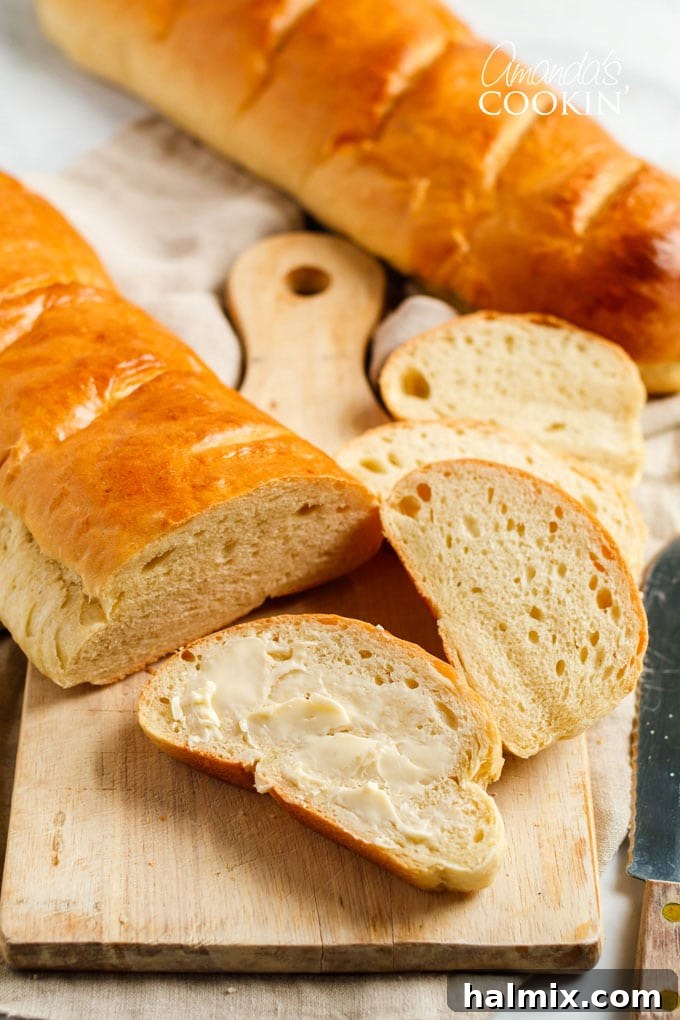 loaf of Italian bread on cutting board, slice of bread with butter