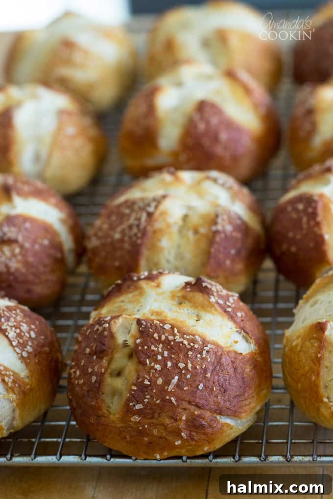 Three organized rows of freshly baked bretzel rolls cooling on a wire rack, ready to be enjoyed.