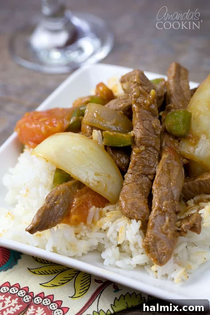 Wok-Tossed Pepper Beef 2 A close up of a white plate with white rice and Chinese pepper steak on top.
