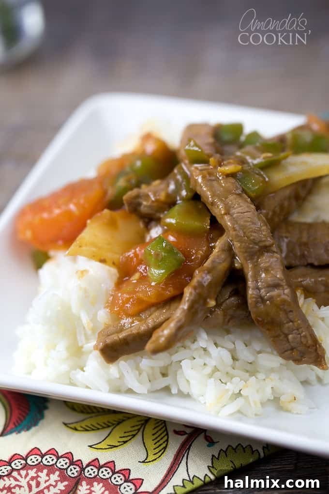 Wok-Tossed Pepper Beef 3 A close up of a white plate with rice and Chinese pepper steak on top.