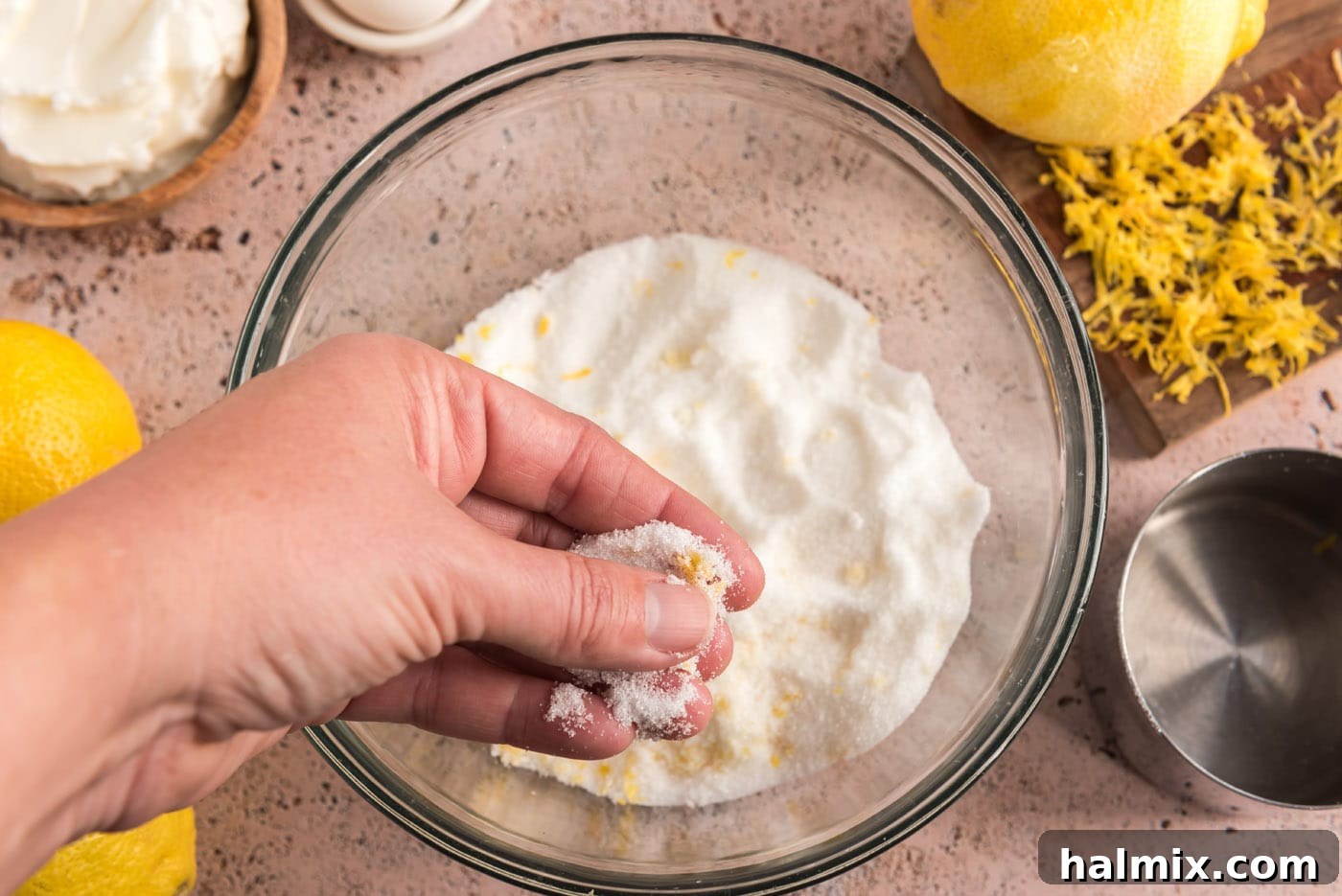 Tangy Lemon Clouds 7 Hands rubbing lemon zest into sugar to infuse flavor