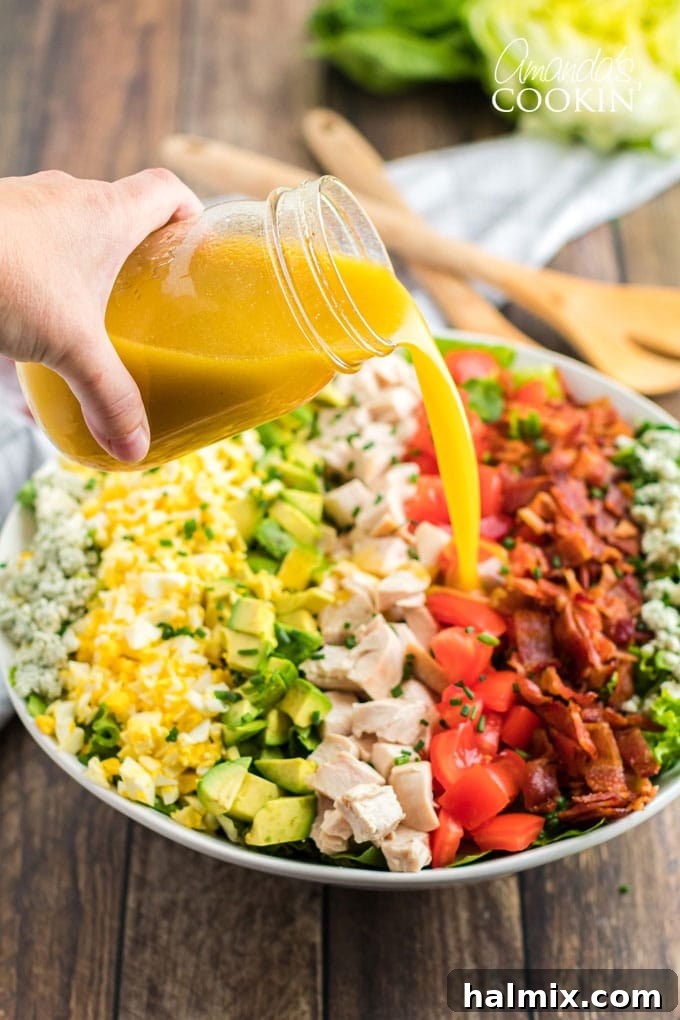 pouring dressing over cobb salad - highlighting the rich, homemade vinaigrette