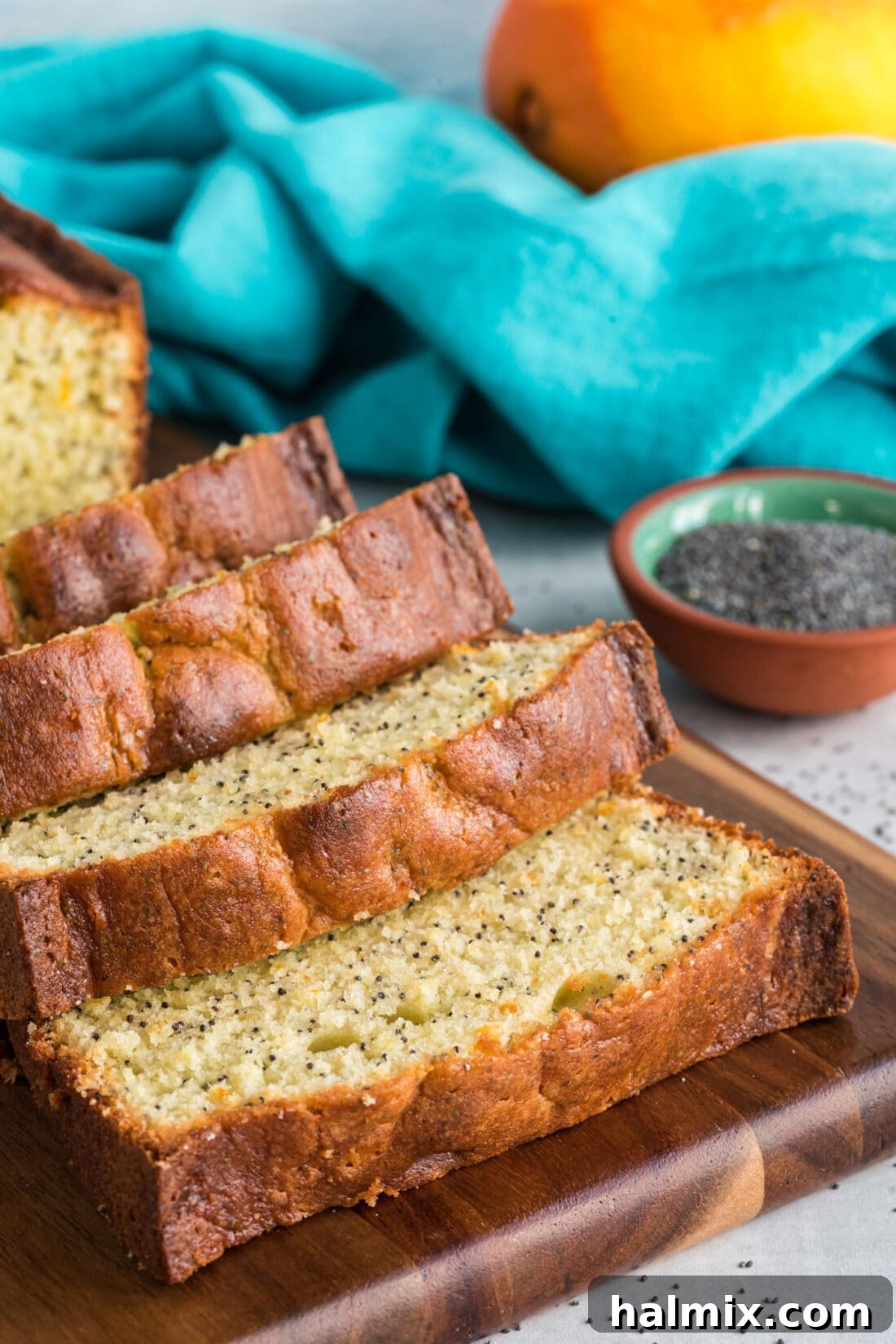 Two loaves of Orange Poppy Seed Pound Cake, one whole and one elegantly sliced, highlighting their golden crust and inviting texture.