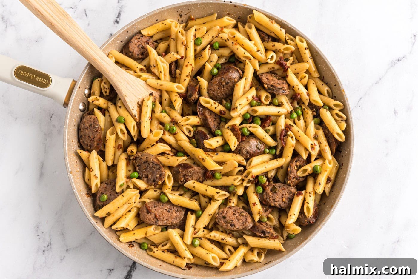 cooked penne pasta added to Italian sausage, peas, and sun dried tomato mixture