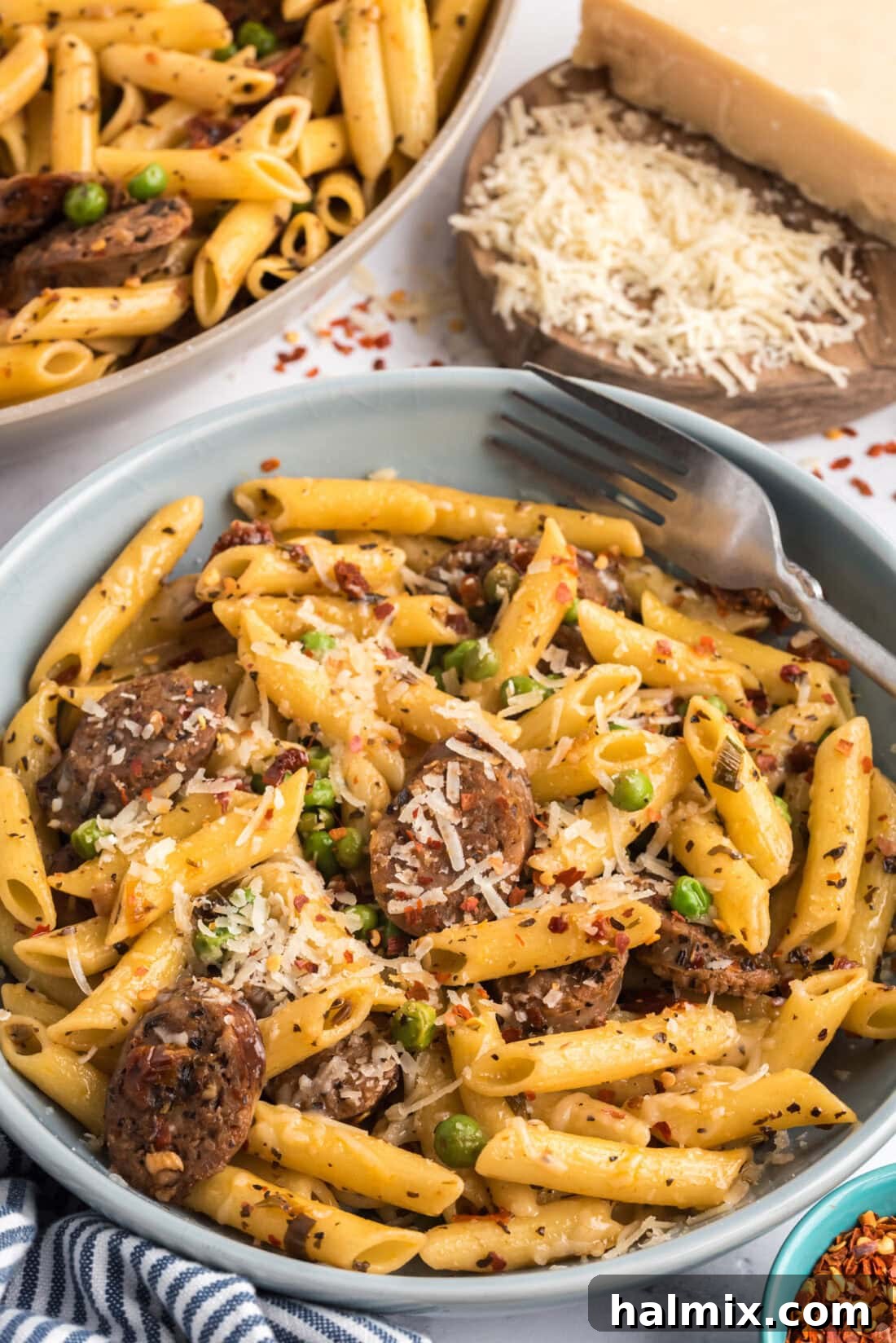 Bowl of Sausage, Penne & Peas topped with shredded cheese