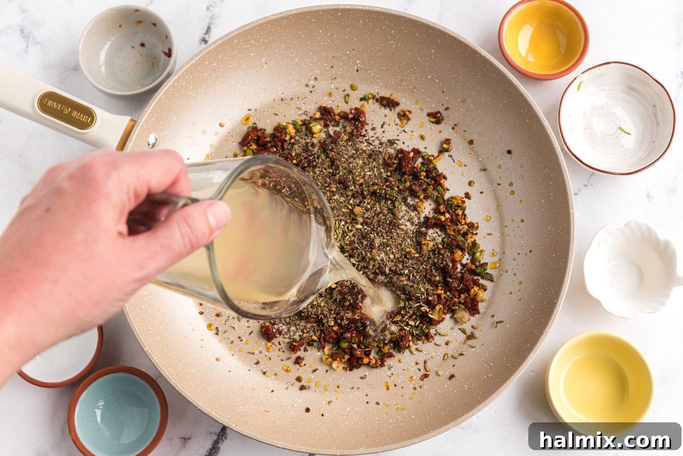 pouring chicken broth into sun dried tomato mixture in a skillet