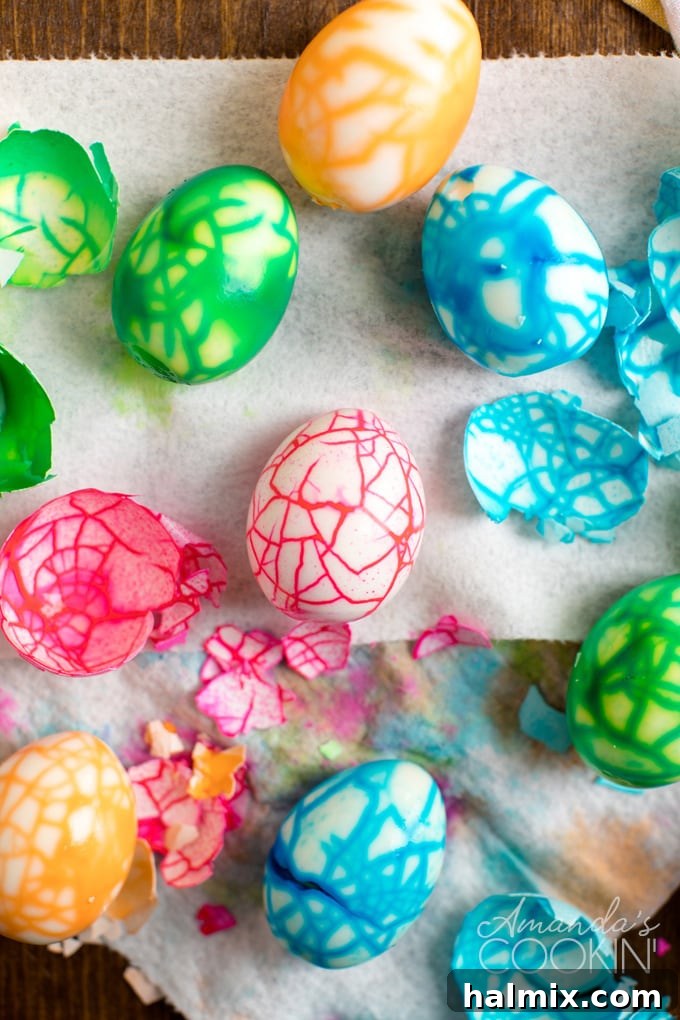 Several cracked colored eggs with their shells still on, resting on paper towels, ready for the coloring process to reveal their unique patterns.