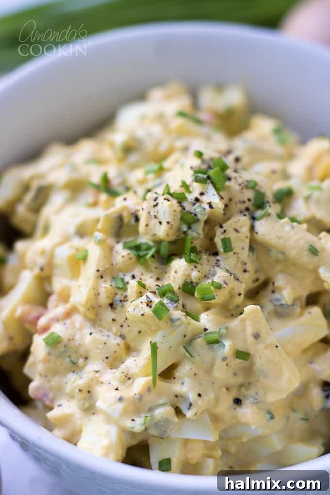 A close-up of a generous serving of egg salad, artfully garnished with extra fresh chives and a sprinkle of black pepper, ready to be enjoyed.