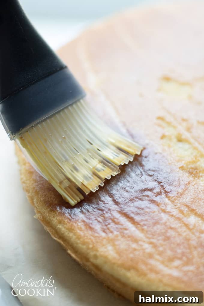brushing espresso syrup on a cake layer